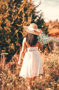 Rear view of woman standing by plants on field