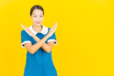 Portrait of smiling young woman against yellow background