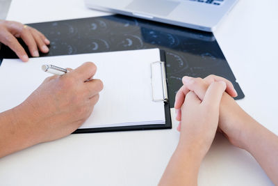 Midsection of woman using mobile phone while sitting on table