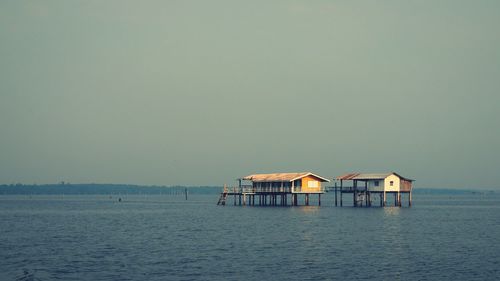 View of stilt houses in sea against clear sky