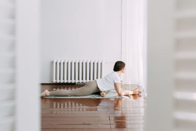 Side view of a young woman sitting on floor