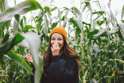 Portrait of smiling young woman standing against plants