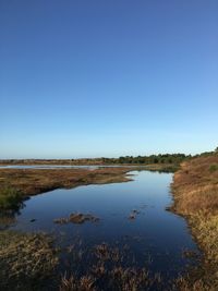 Scenic view of lake against clear blue sky