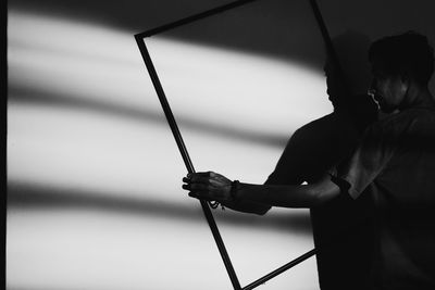 Rear view of silhouette man holding fishing rod