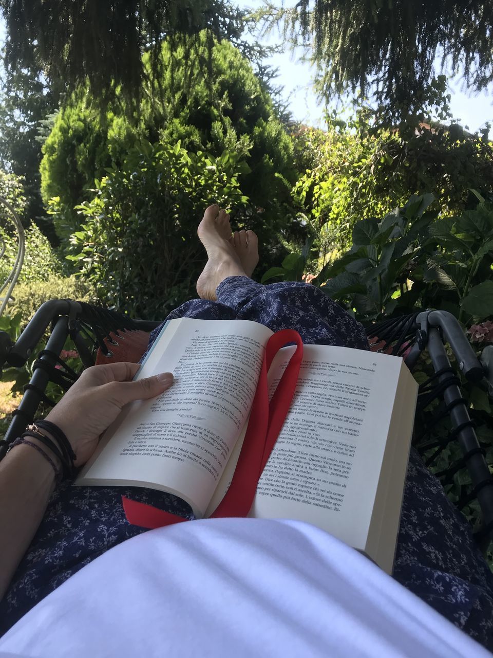 LOW SECTION OF WOMAN READING BOOK AGAINST TREE