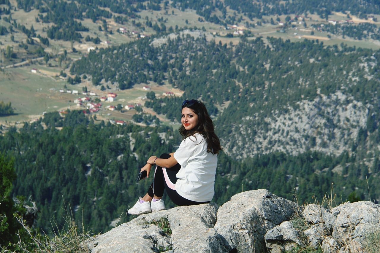 one person, mountain, young adult, rock, solid, rock - object, leisure activity, beauty in nature, casual clothing, nature, scenics - nature, young women, day, lifestyles, adult, environment, women, sitting, real people, mountain range, outdoors, beautiful woman