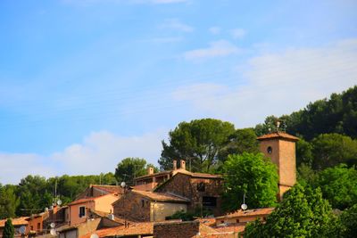 Houses by trees in town against sky