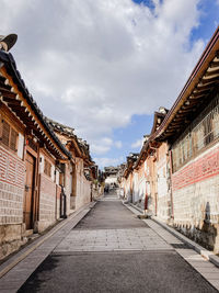 Empty road amidst buildings against sky