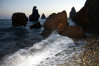 Rocks in sea against clear sky