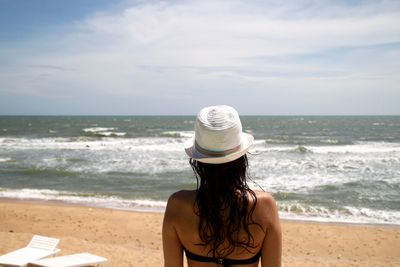 Rear view of woman standing on beach against sky