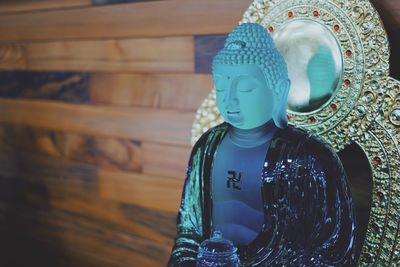 Close-up of buddha statue against wooden wall