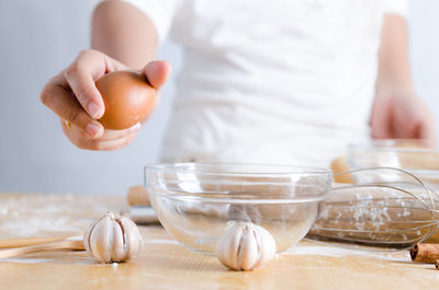 Close-up of man breaking egg in container on table