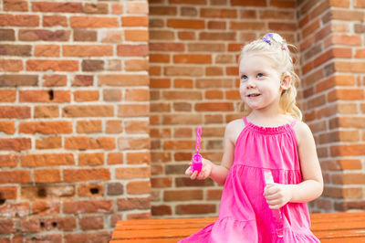 Portrait of girl standing against brick wall