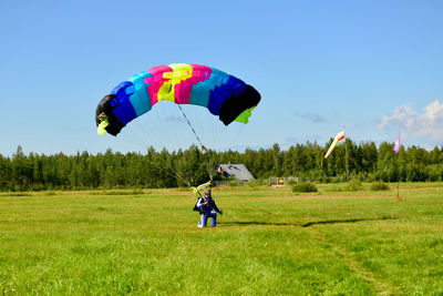 Full length of men flying kite on field against sky