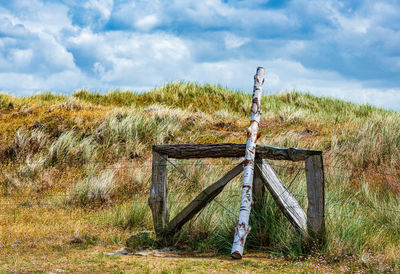 Wooden posts on field against sky