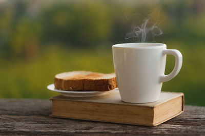 Coffee cup with bread on green blurred background