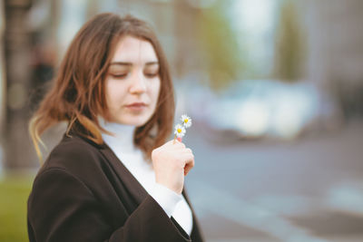 Beautiful woman holding daisies in city