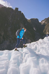 Full length side view of woman on snowcapped mountain