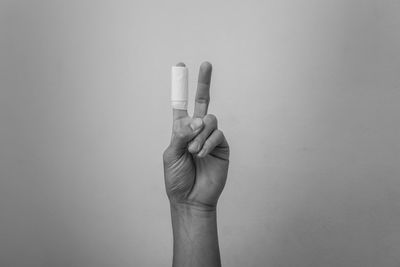 Close-up of person making peace sing against wall