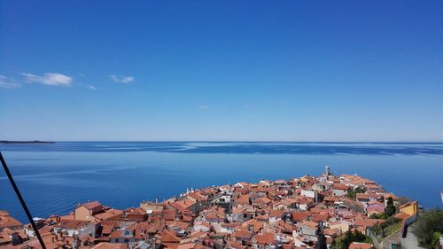 High angle view of townscape by sea against blue sky