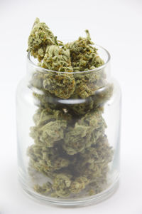 Close-up of ice cream in glass jar on table against white background