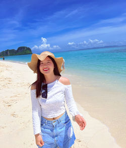 Young woman standing at beach against sky