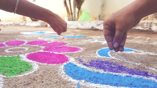 Cropped hands making rangoli on floor