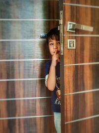 Portrait of boy looking away while standing on door