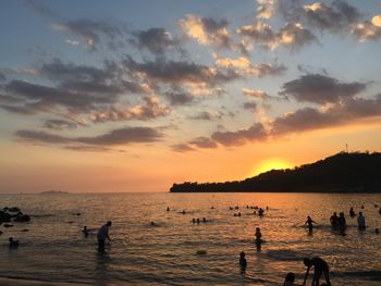 Silhouette people on beach against sky during sunset