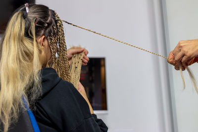 A stylist mother getting her teenage daughter senegalese braids in her home. 