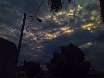 Low angle view of silhouette trees against cloudy sky