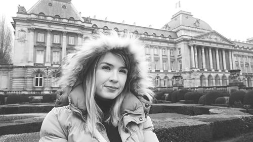 Woman wearing warm clothing standing against building in city