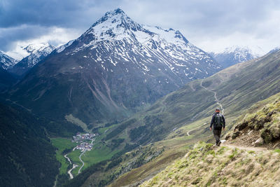 Rear view of person on snowcapped mountain against sky