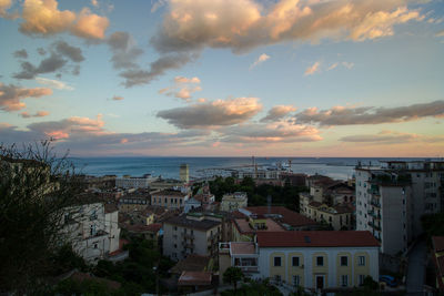 High angle view of cityscape and sea against cloudy sky