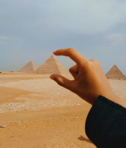 Cropped hand of woman gesturing against pyramid