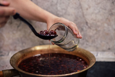 Midsection of person pouring drink in glass