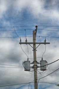 Low angle view of electricity pylon against cloudy sky