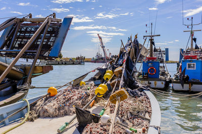 Boats moored at harbor against sky