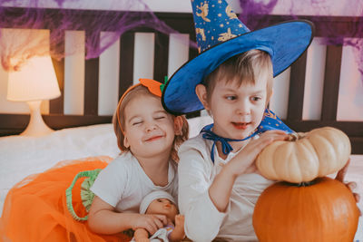 Two little kids in festive halloween costumes with pumpkins having fun. family spending time 