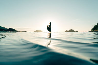 Silhouette man on beach against sky during sunset