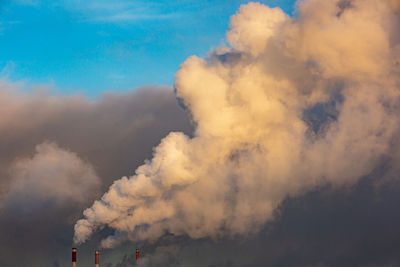 Low angle view of smoke emitting from factory against sky