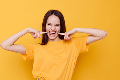 Portrait of smiling teenager girl against yellow background