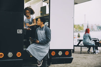 Female owner and assistant discussing in food truck