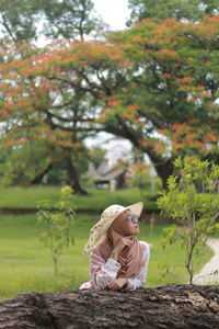 Woman sitting on rock by tree