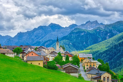 Houses on townscape by mountains against sky