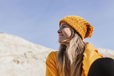 Portrait of young woman looking away against sky