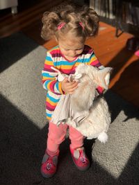 High angle view of girl holding stuffed toy while standing at home