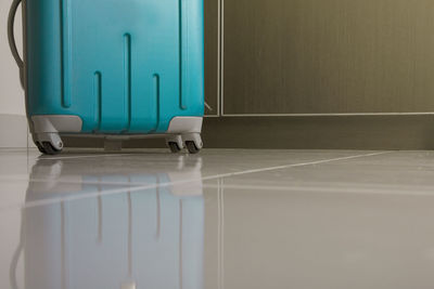 Surface level shot of turquoise wheeled luggage on tiled floor