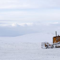 Snowplow on snow covered field against sky