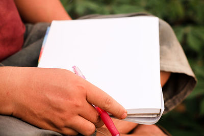 Cropped hand of person holding blank paper in city